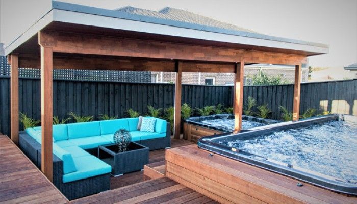 A gazebo with a couch and a hot tub in the backyard.