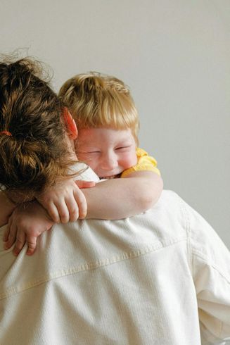 A little boy is hugging a woman 's back.