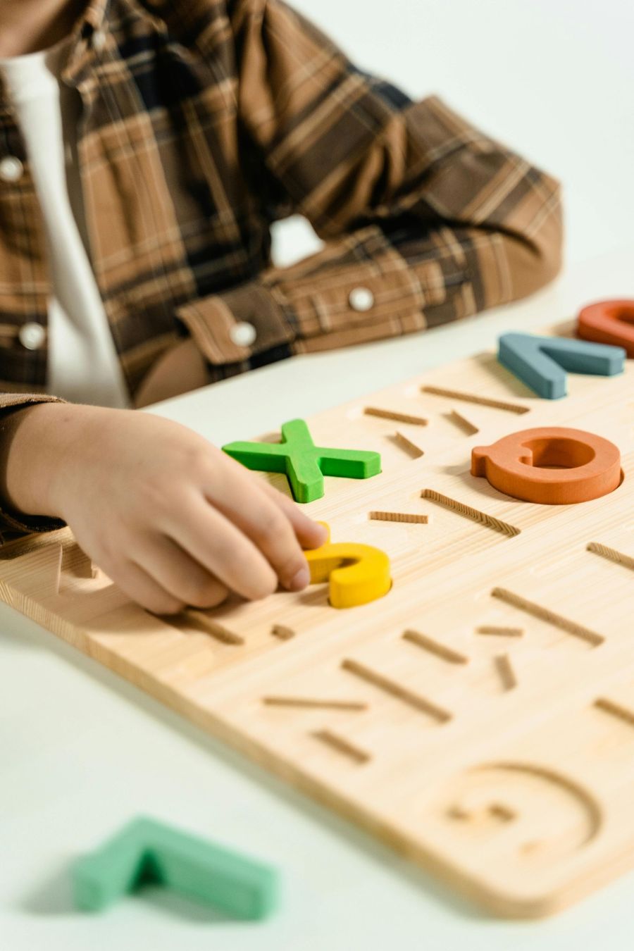 A child is playing with a wooden board with letters and numbers on it.