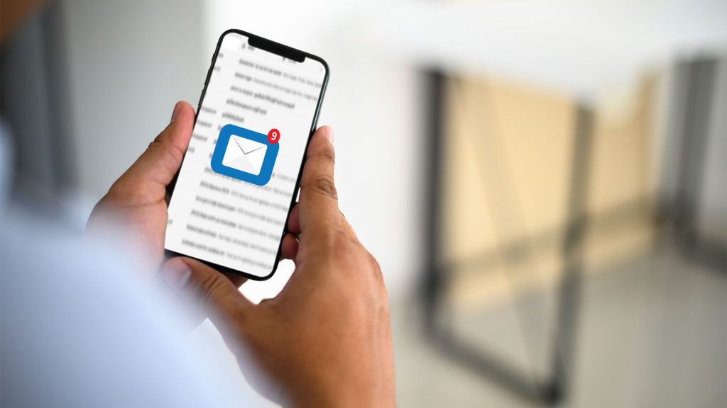 Pessoa segurando um smartphone que exibe a caixa de entrada de e-mail com uma notificação de mensagem não lida.