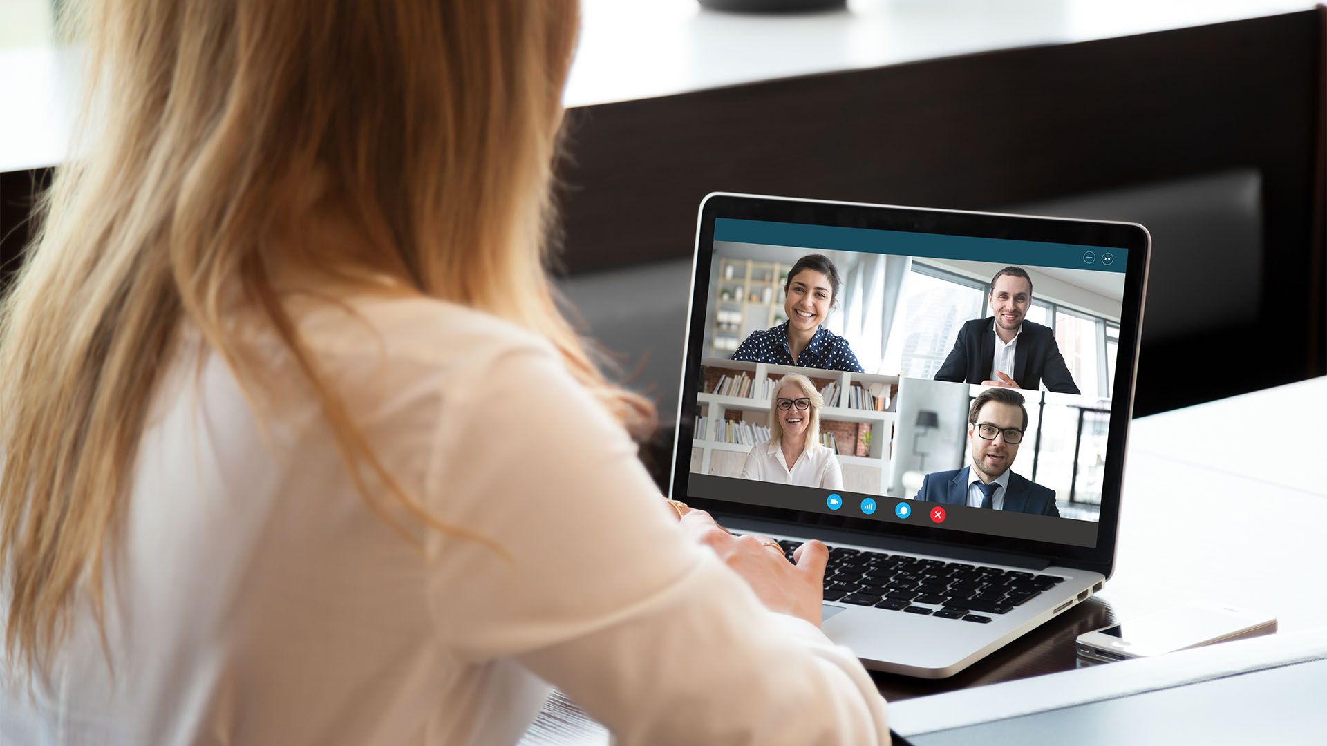 Mulher usando laptop para uma videoconferência com outras três pessoas.