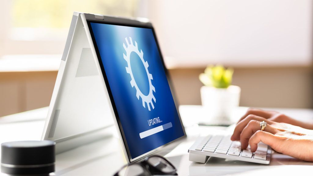 Laptop com tela de carregamento e mãos digitando no teclado.