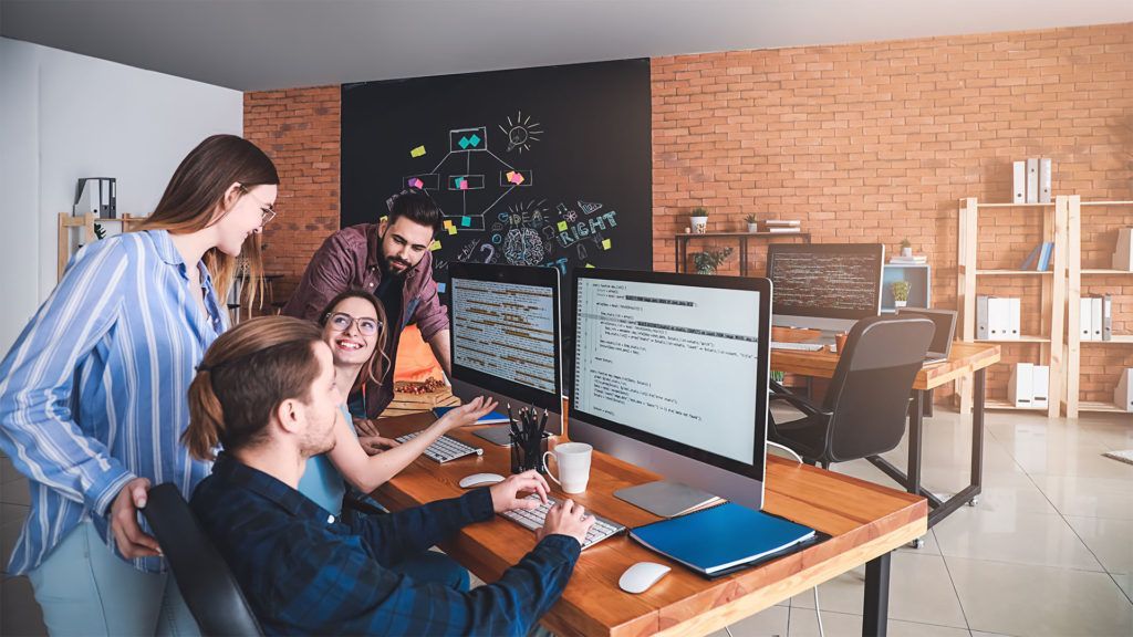 Pessoas trabalhando em computadores em um escritório moderno, um homem trabalhando com uma equipe.