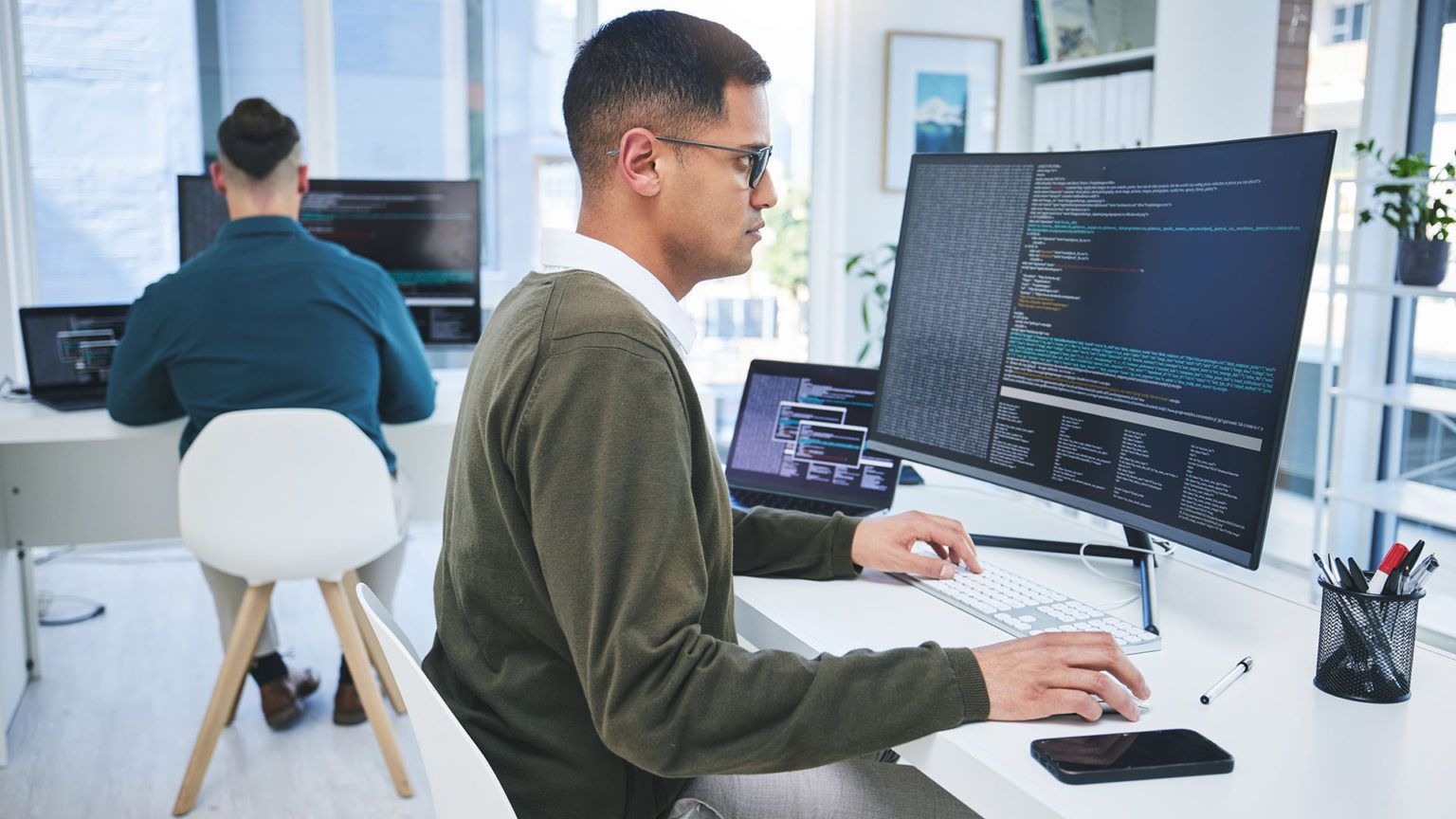 Profissional de TI analisando código em monitores, simbolizando ransomware remoto.