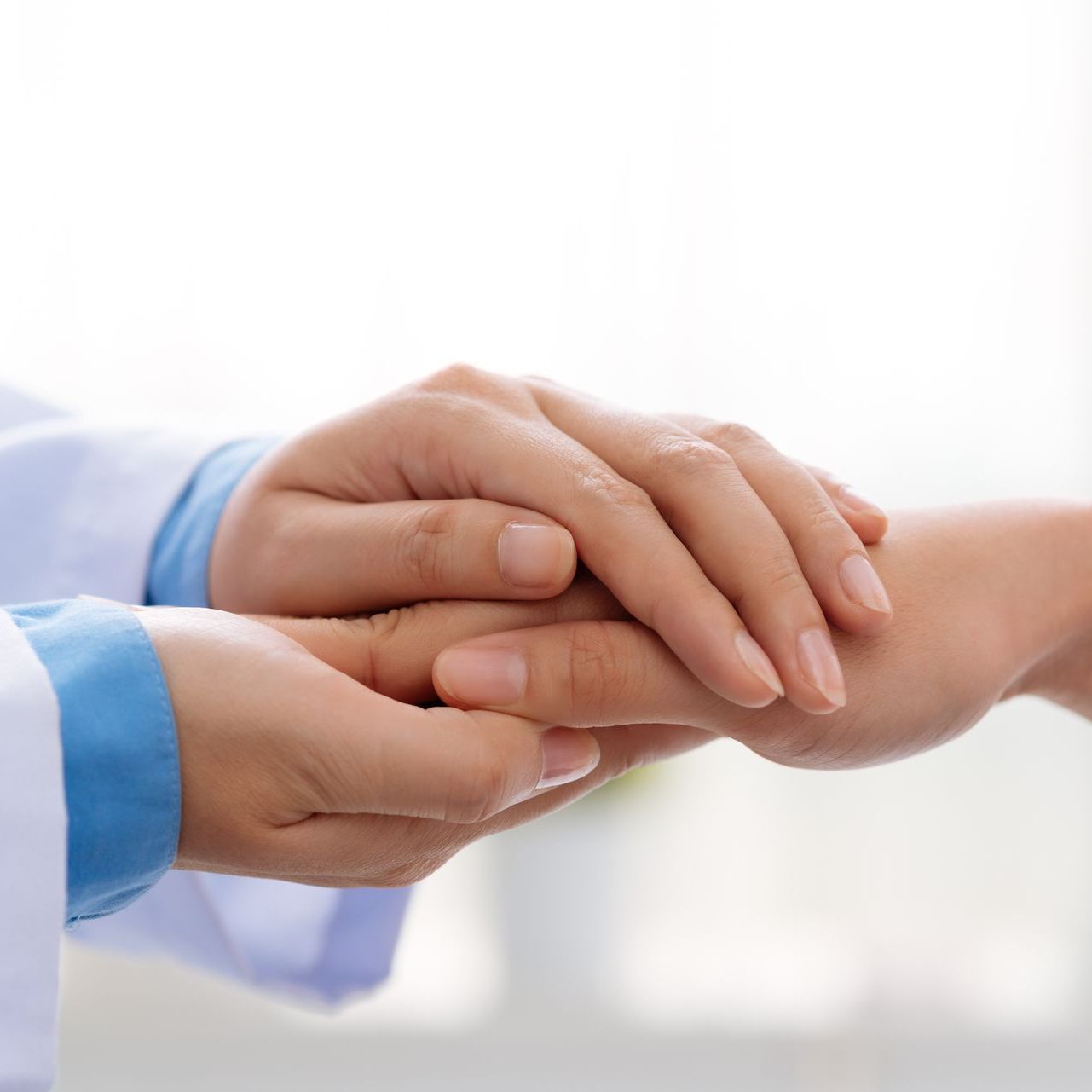 A doctor is holding the hand of a patient.