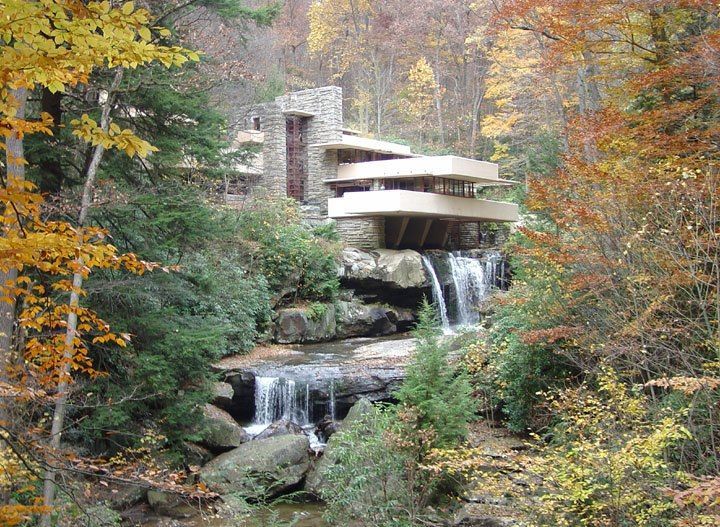 A waterfall in the middle of a forest with a house in the background