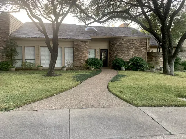 A house with a walkway leading to it and trees in front of it