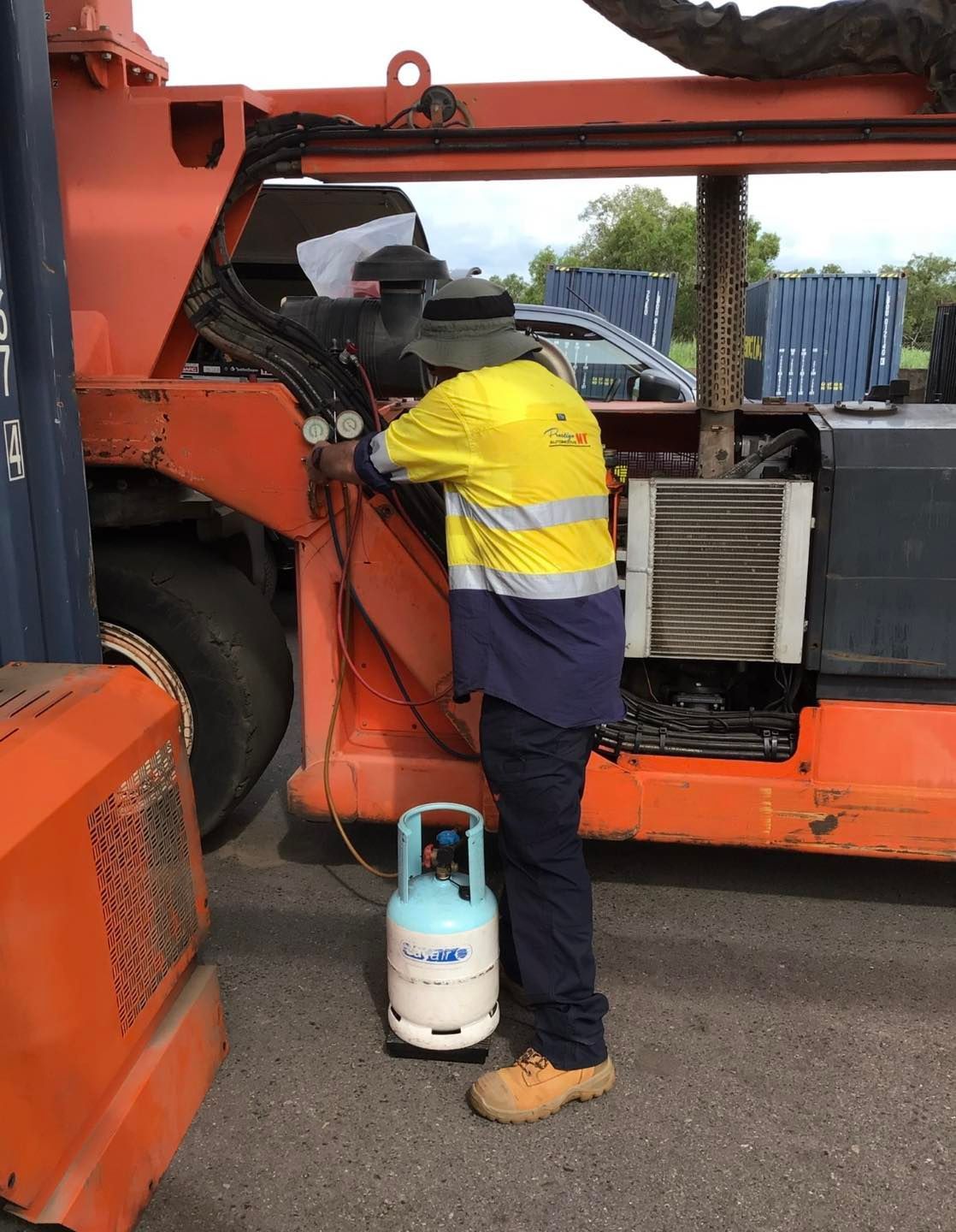 Airconditioning unit in a truck being looked at by a man in yellow jacket— Prestige Automotive NT In Yarrawonga, NT