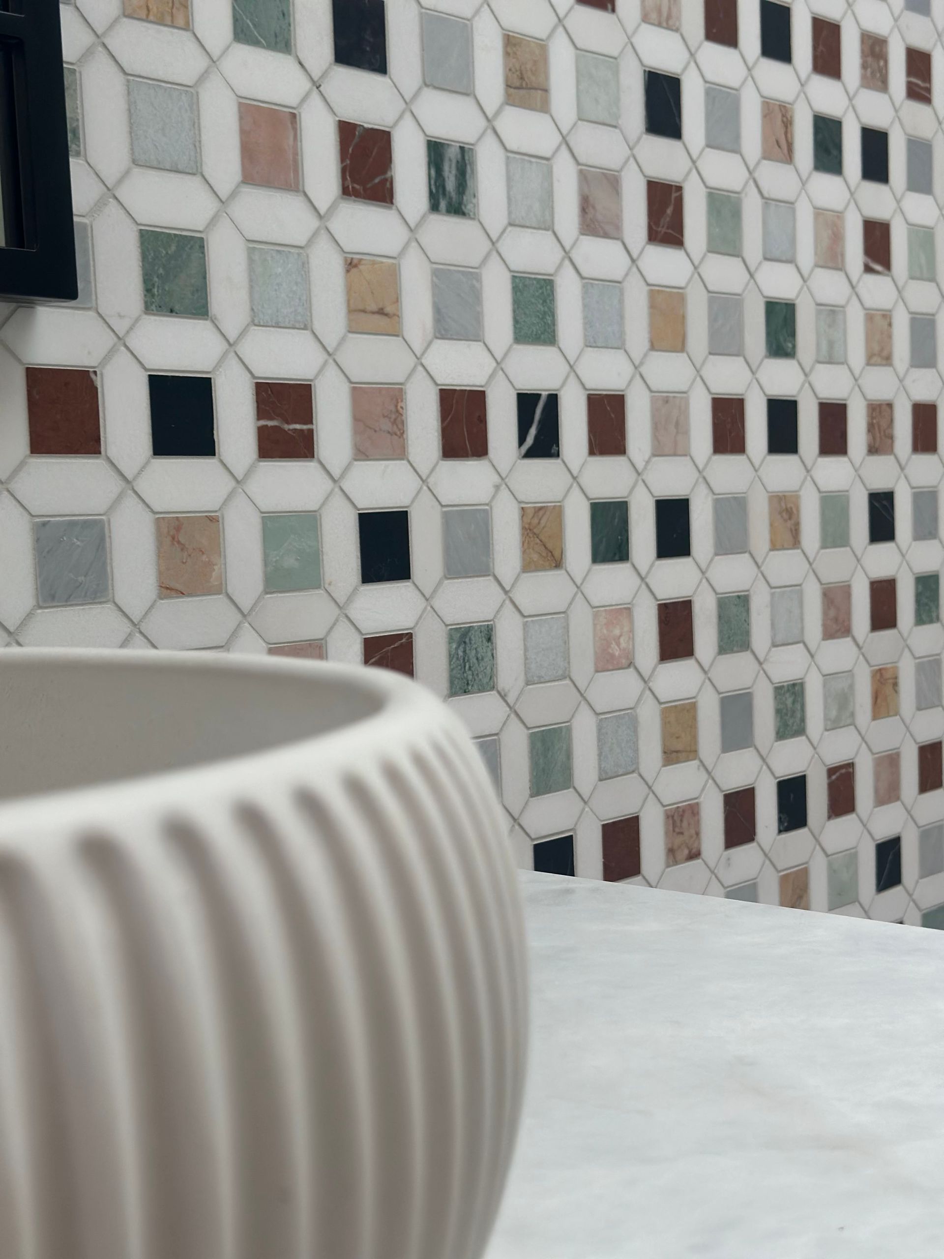 White, Ribbed Vase on Marble Surface With Patterned Tile Wall of Mixed Colors in Background — Stone Arc in Kincumber, NSW