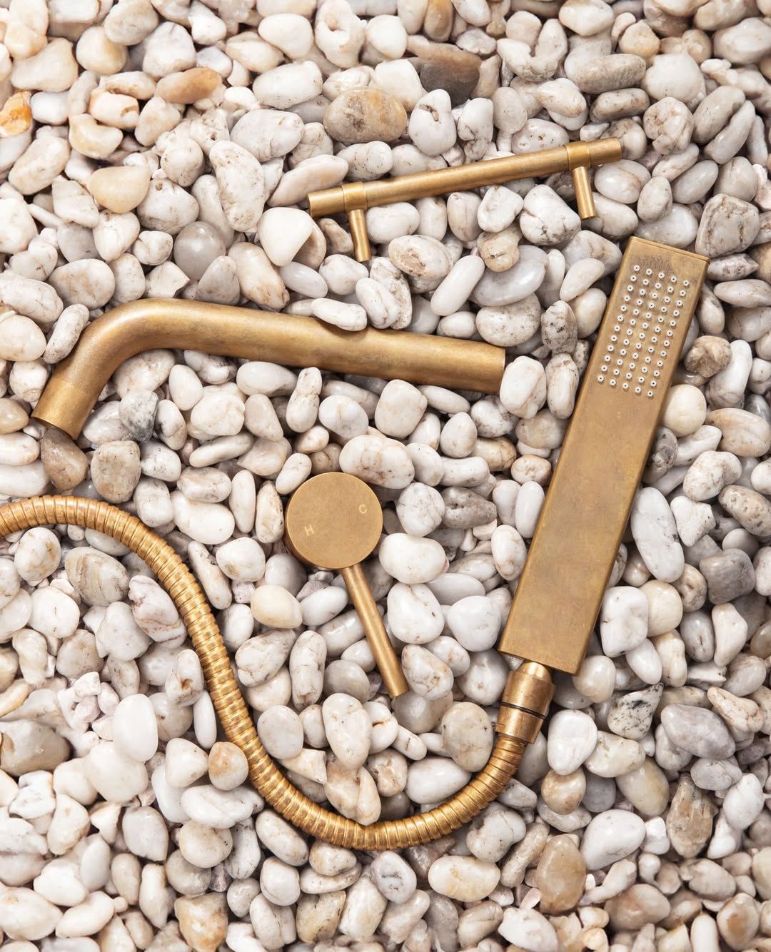 Gold-Colored Shower Fixtures: Handheld Showerhead, Faucet, and Shower Arm on White Stones — Stone Arc in Kincumber, NSW