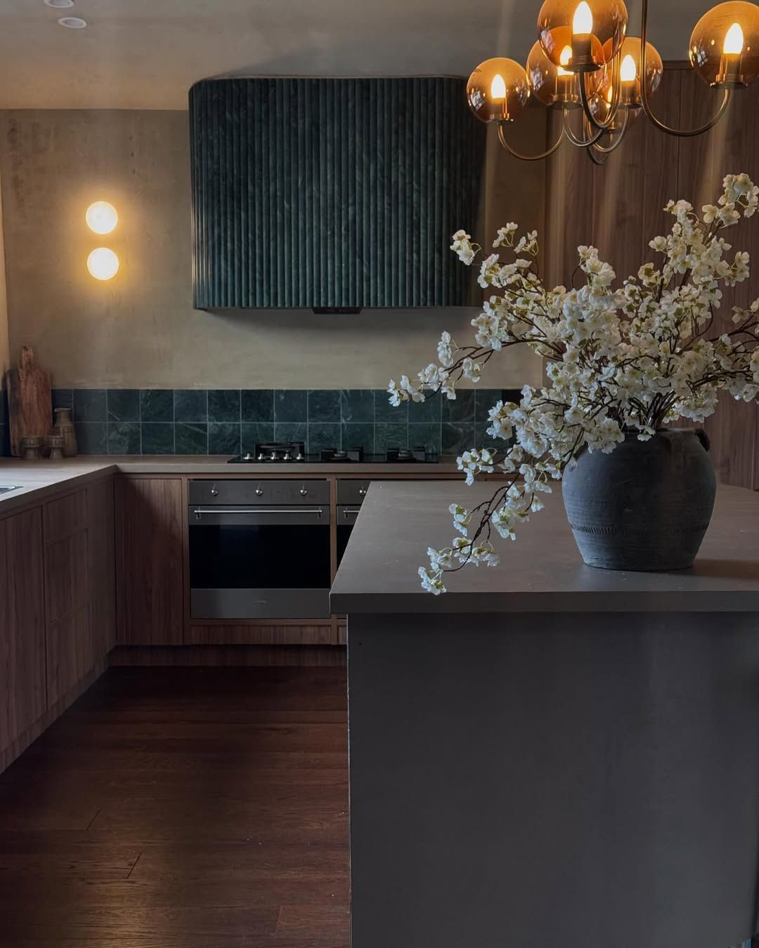 Modern Kitchen With Teal Range Hood, Oven, Wooden Cabinets and Vase of White Flowers — Stone Arc in Kincumber, NSW