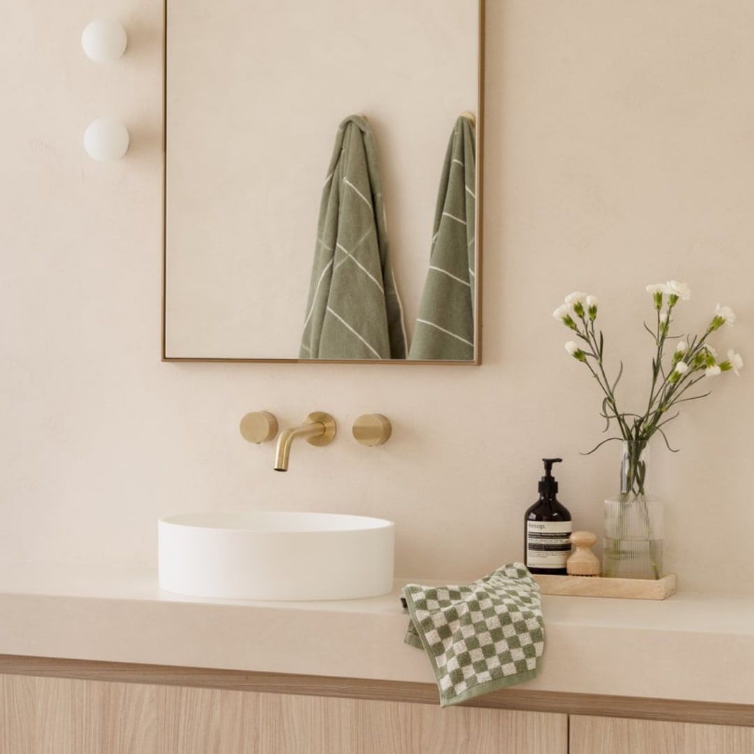 Bathroom With a Round White Sink, Gold Faucet, and Green Towels, on a Beige Countertop — Stone Arc in Kincumber, NSW