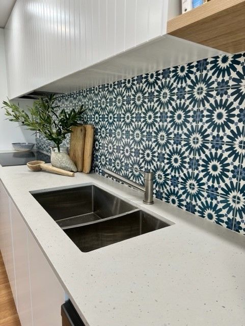 A Kitchen With A Stainless Steel Sink And A Blue And White Tile Backsplash  — Stone Arc in Kincumber, NSW