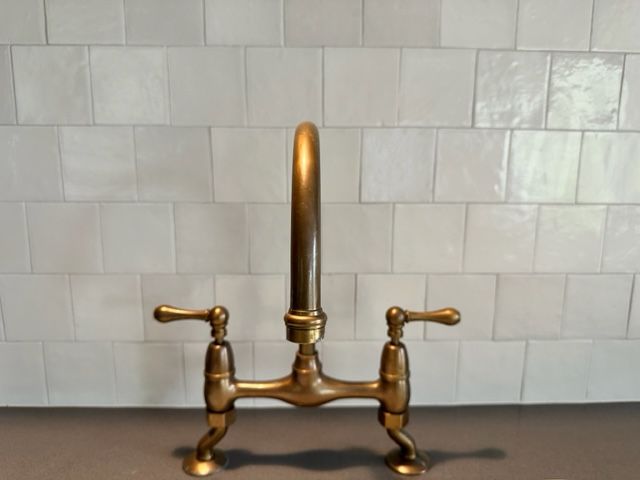 A Brass Faucet Is Sitting On A Counter In Front Of A White Tiled Wall  — Stone Arc in Kincumber, NSW