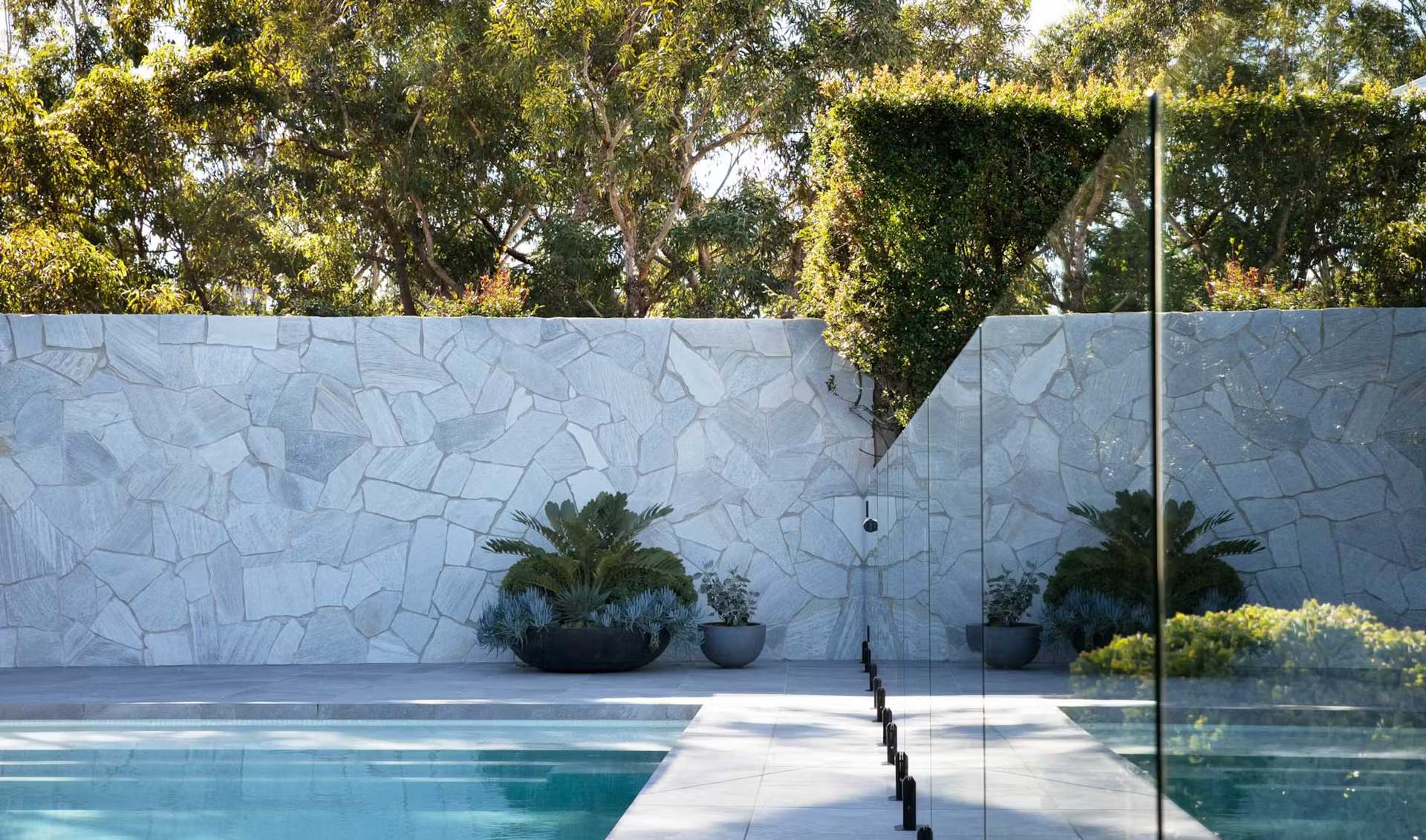 Poolside Scene With Stone Wall, Plants, Glass Fence, and Trees — Stone Arc in Kincumber, NSW