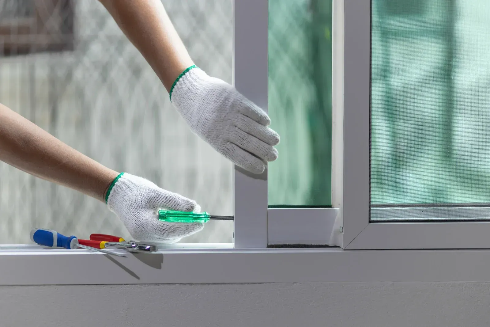 A person is fixing a window with a screwdriver.
