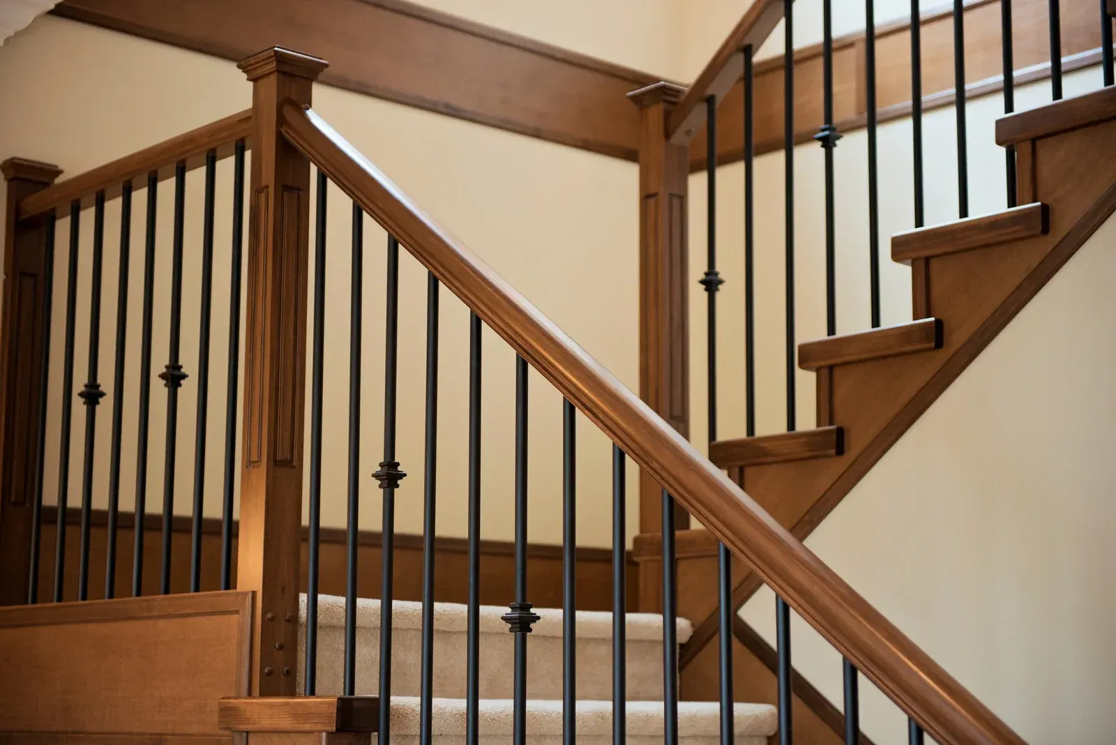 A wooden staircase with a black railing and a carpeted floor.