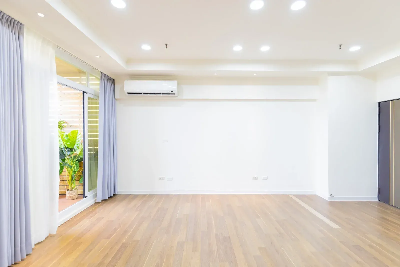 A large empty room with hardwood floors and white walls.
