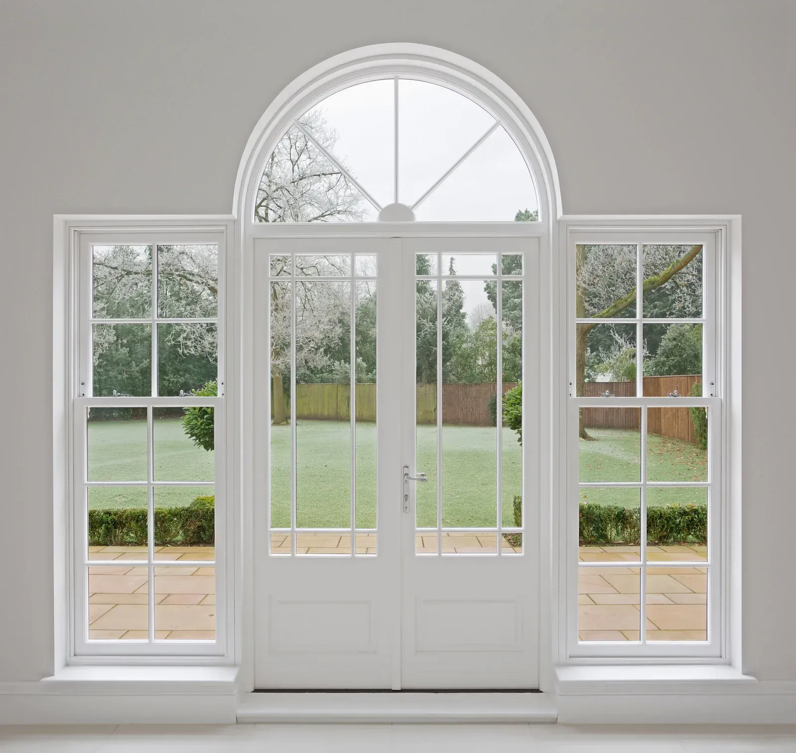 A white door with arched windows leading to a garden