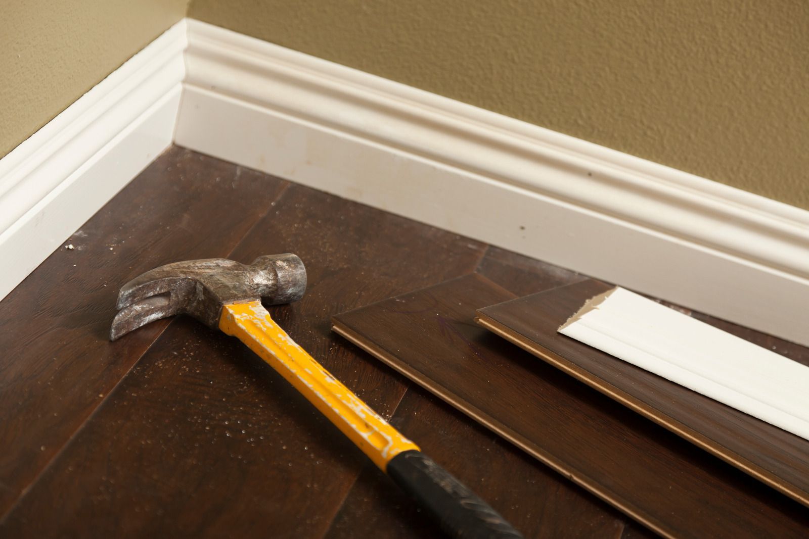 A corner of a room with a wooden floor and white molding.
