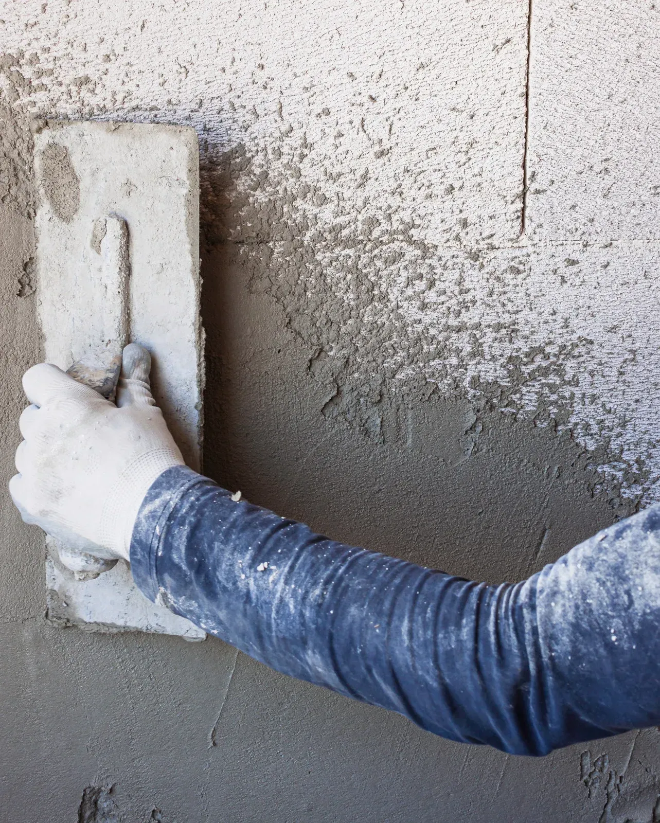 A person is plastering a wall with a trowel