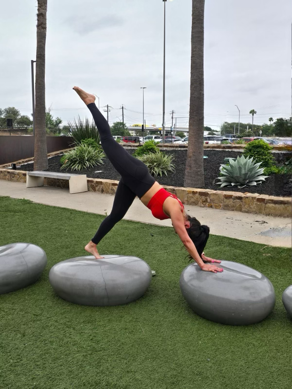 A woman is doing a handstand on a rock