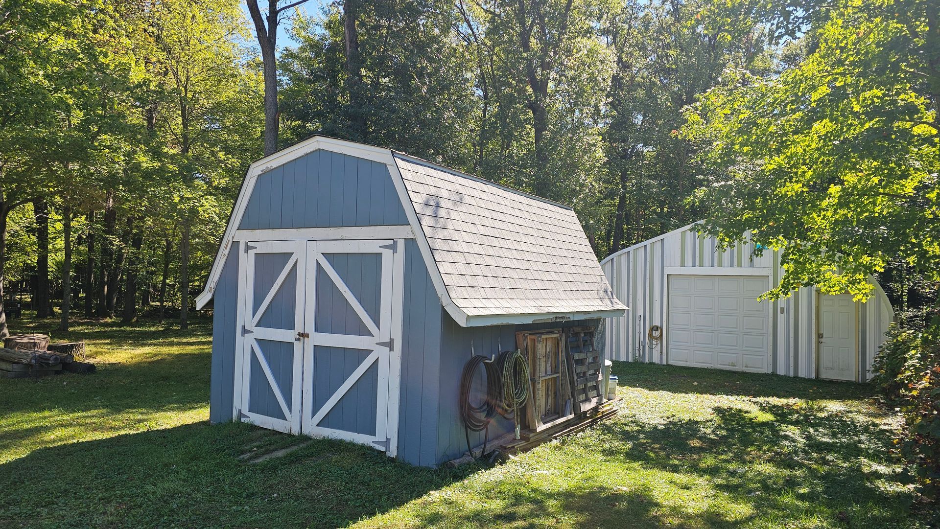 A blue and white barn is sitting in the middle of a lush green field.