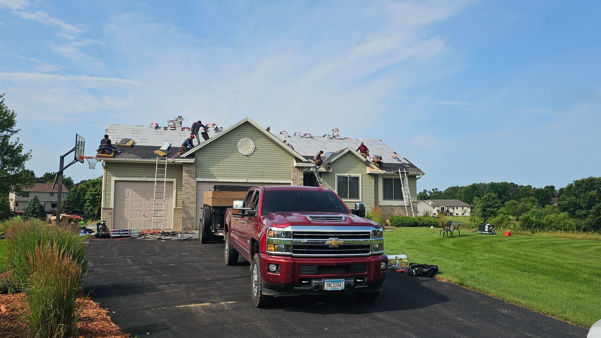 A red truck is parked in front of a house under construction.
