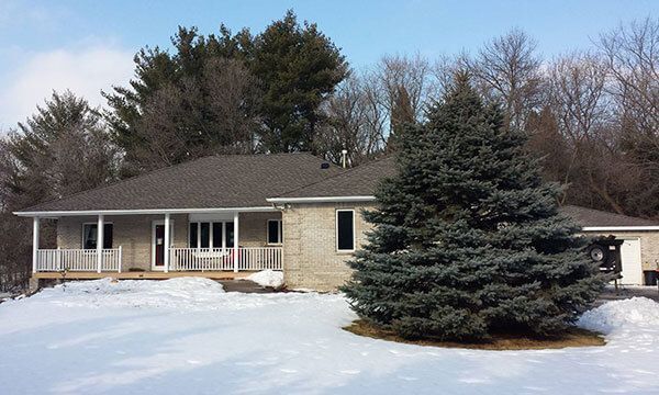 A house with a porch and a tree in front of it