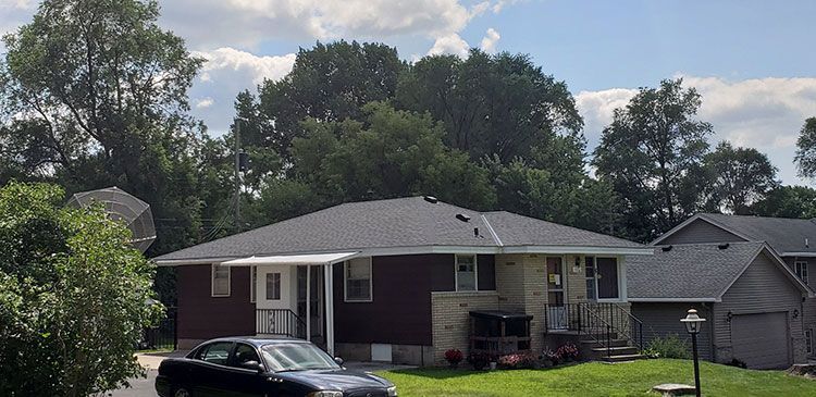 A car is parked in front of a house in a residential area.