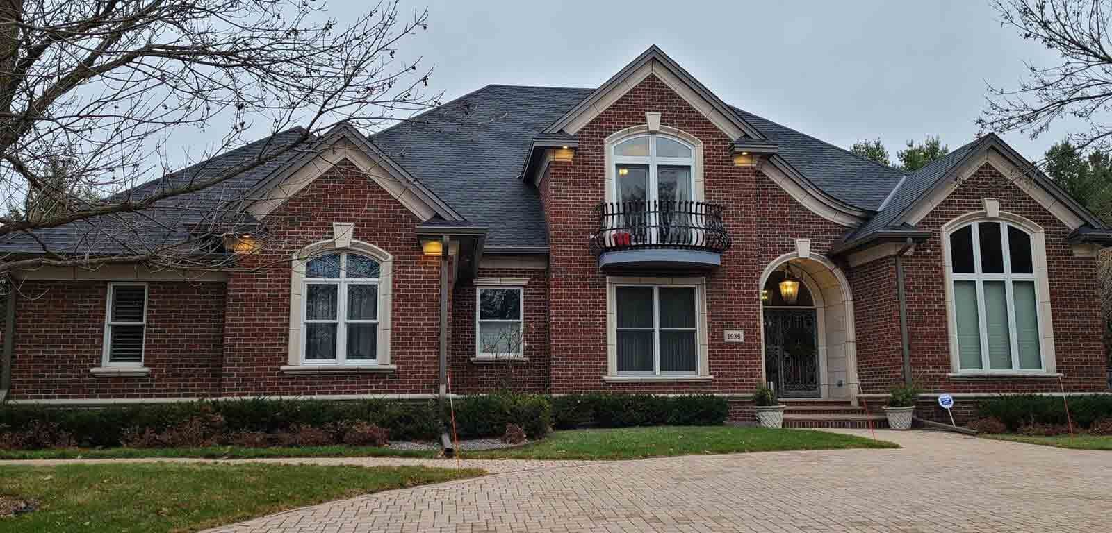 A large brick house with a blue roof and white windows.