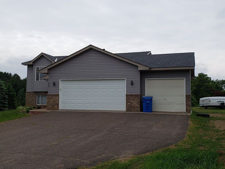 A house with a large garage and a blue trash can in front of it