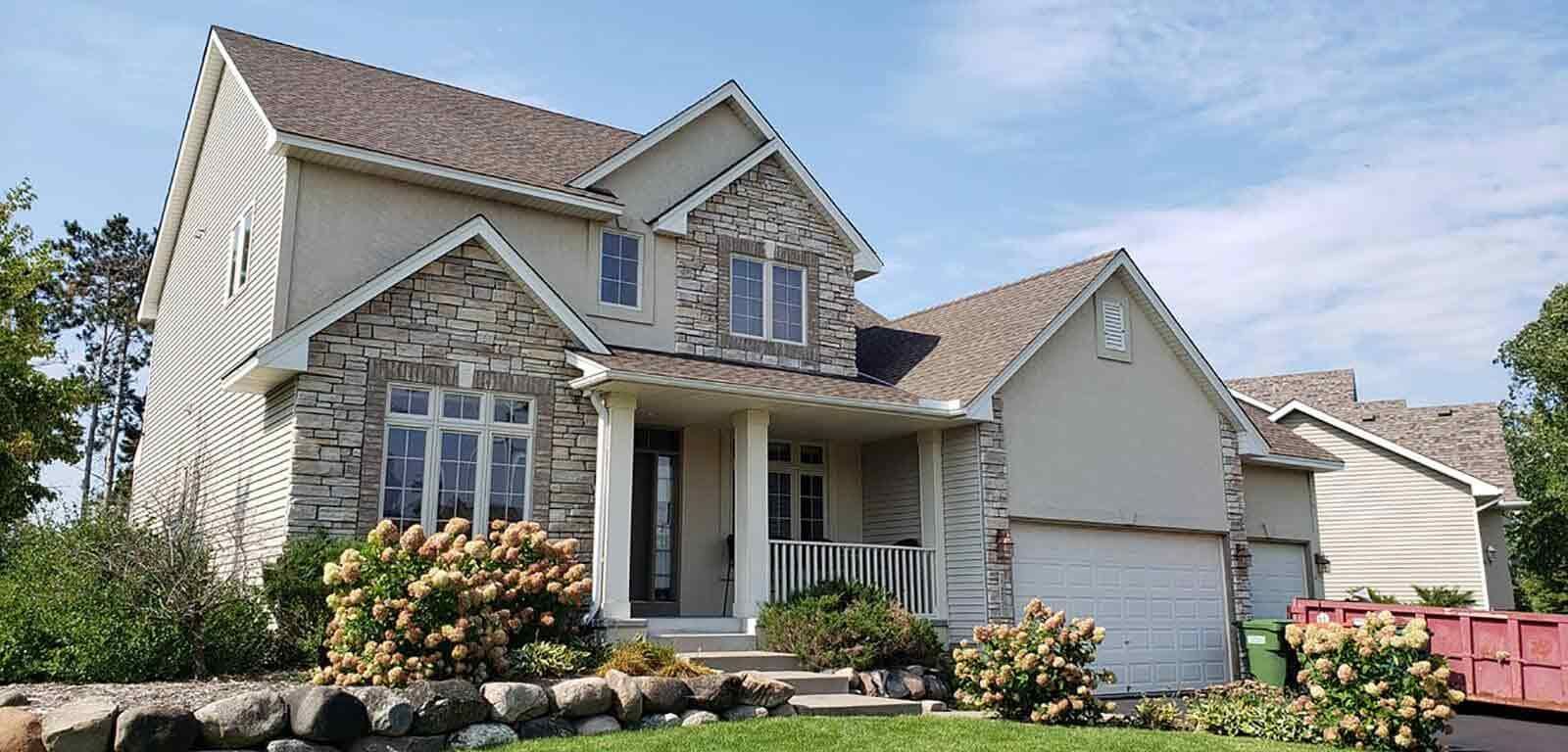 A large house with a red dumpster in front of it.