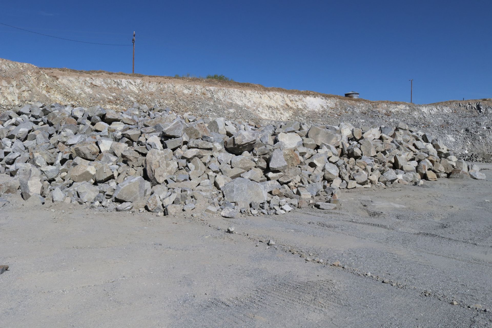 A pile of rocks in a dirt field with a blue sky in the background