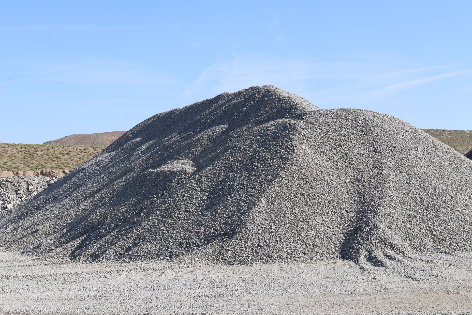 A large pile of gravel is sitting on top of a dirt field.