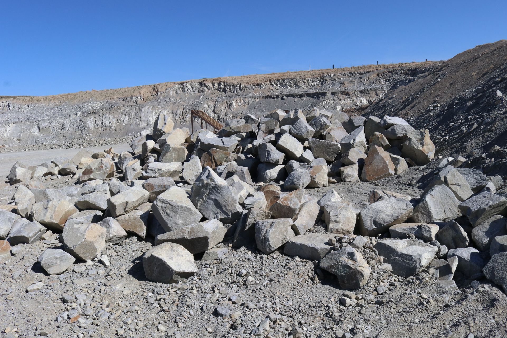 A pile of rocks in a dirt field with a blue sky in the background