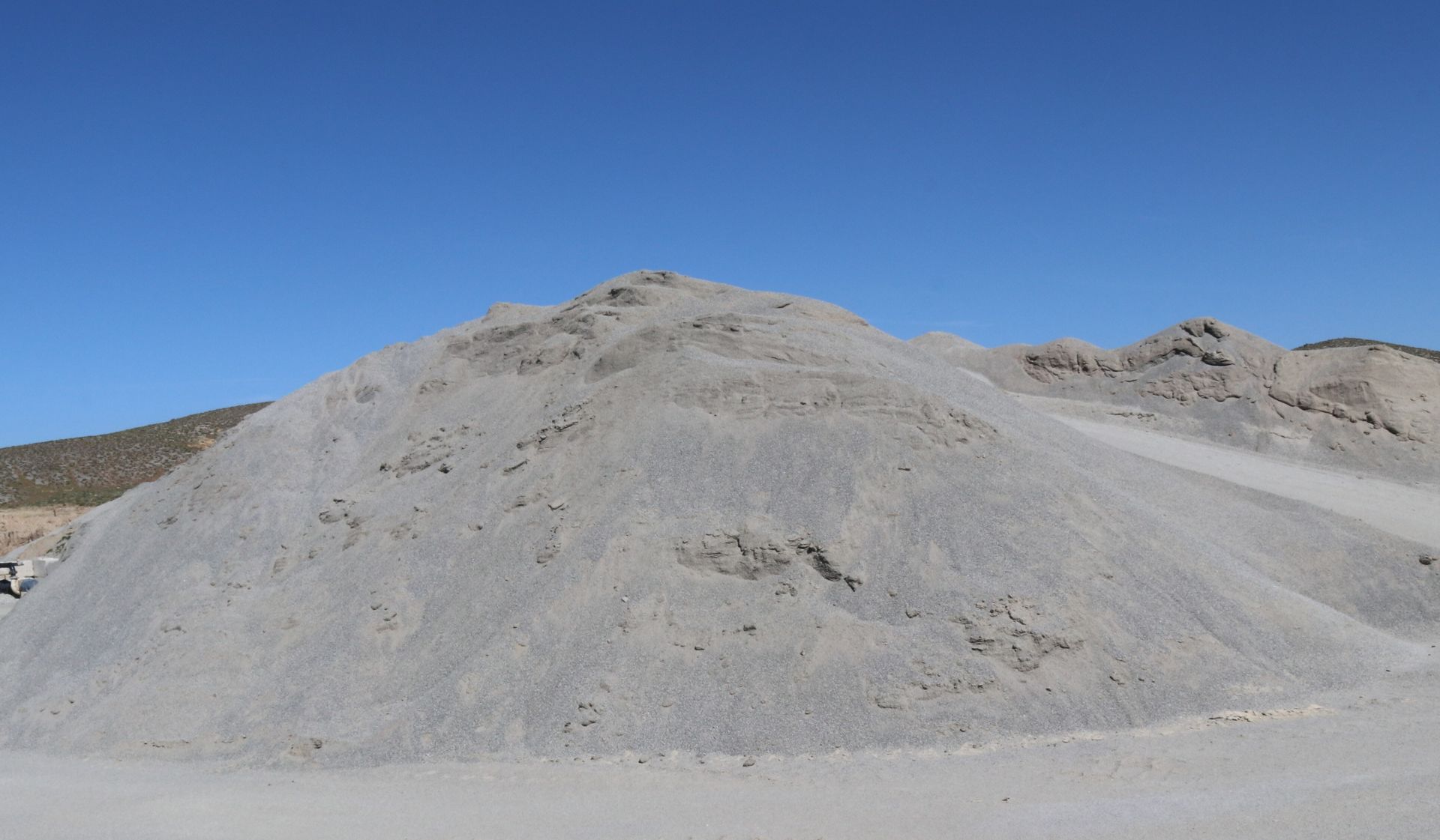 A large pile of gravel is sitting on top of a dirt hill.