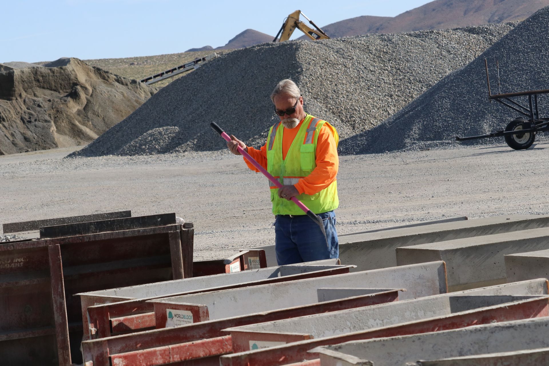 A man in a safety vest is standing in front of a pile of rocks