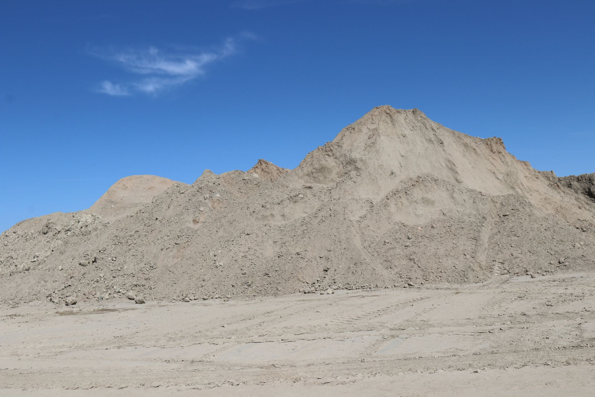 A large pile of dirt in the desert with a mountain in the background