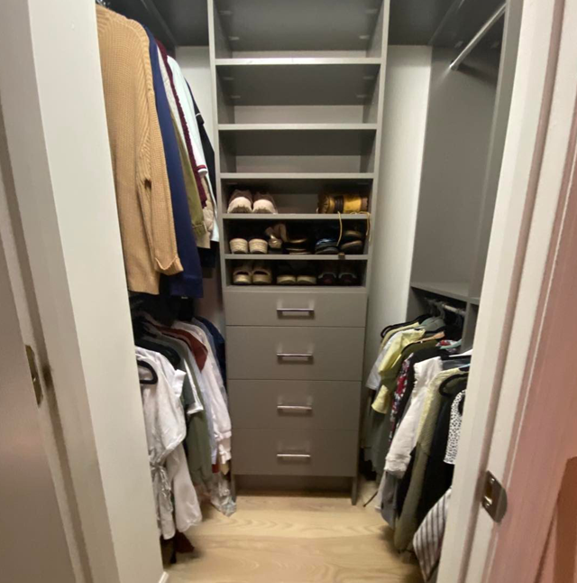 Walk-in closet with gray shelving, drawers, and hanging clothes, with light wood floor.