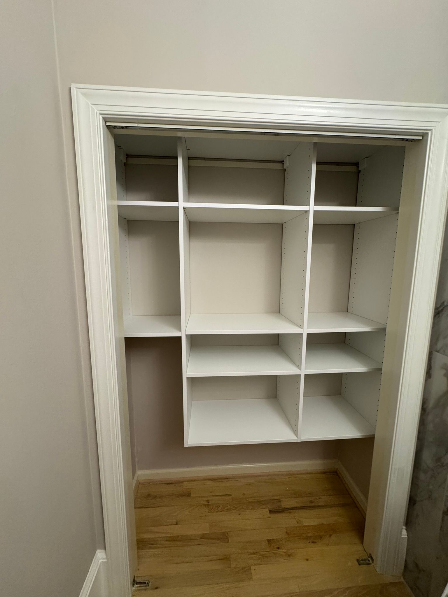 White built-in shelving unit inside a doorway, with multiple compartments on a light wood floor.