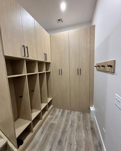Light wood entry with built-in storage cabinets and cubbies. A coat rack hangs on the right wall.
