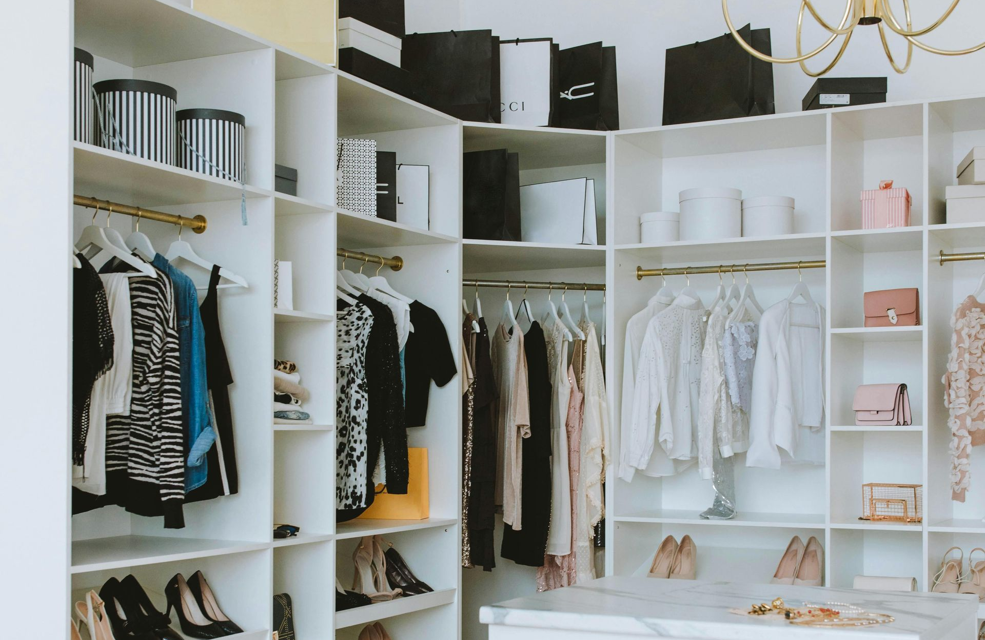 White walk-in closet with organized clothing, shelves, and accessories.
