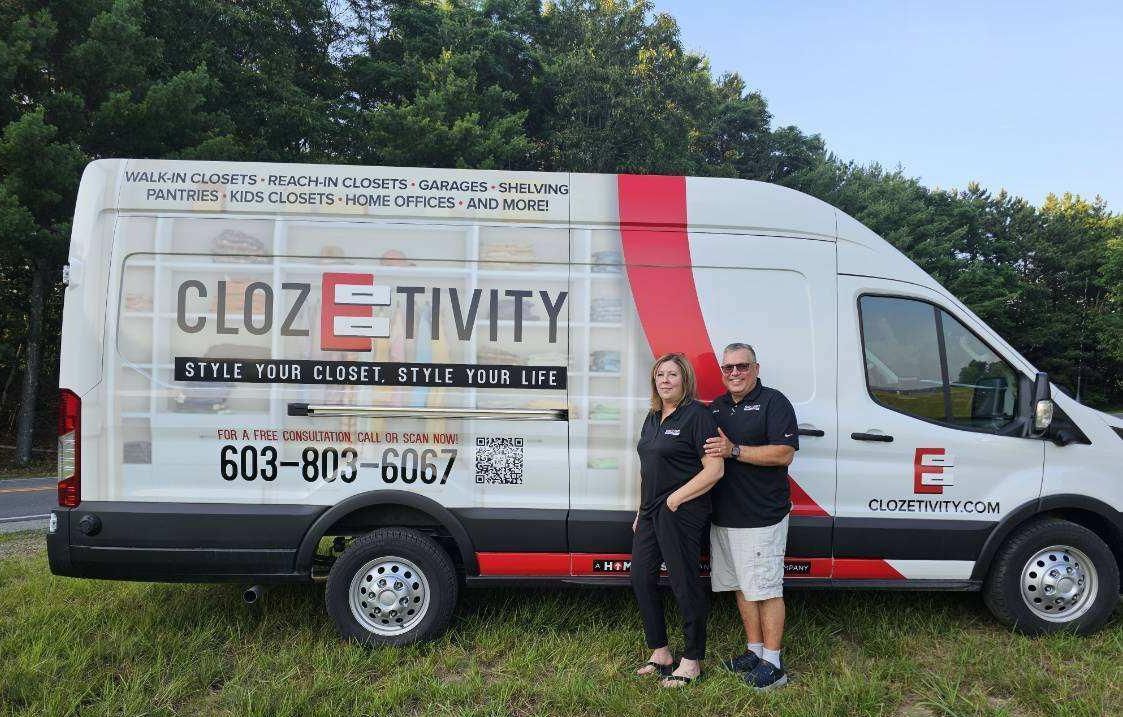 Two people stand next to a white van with 