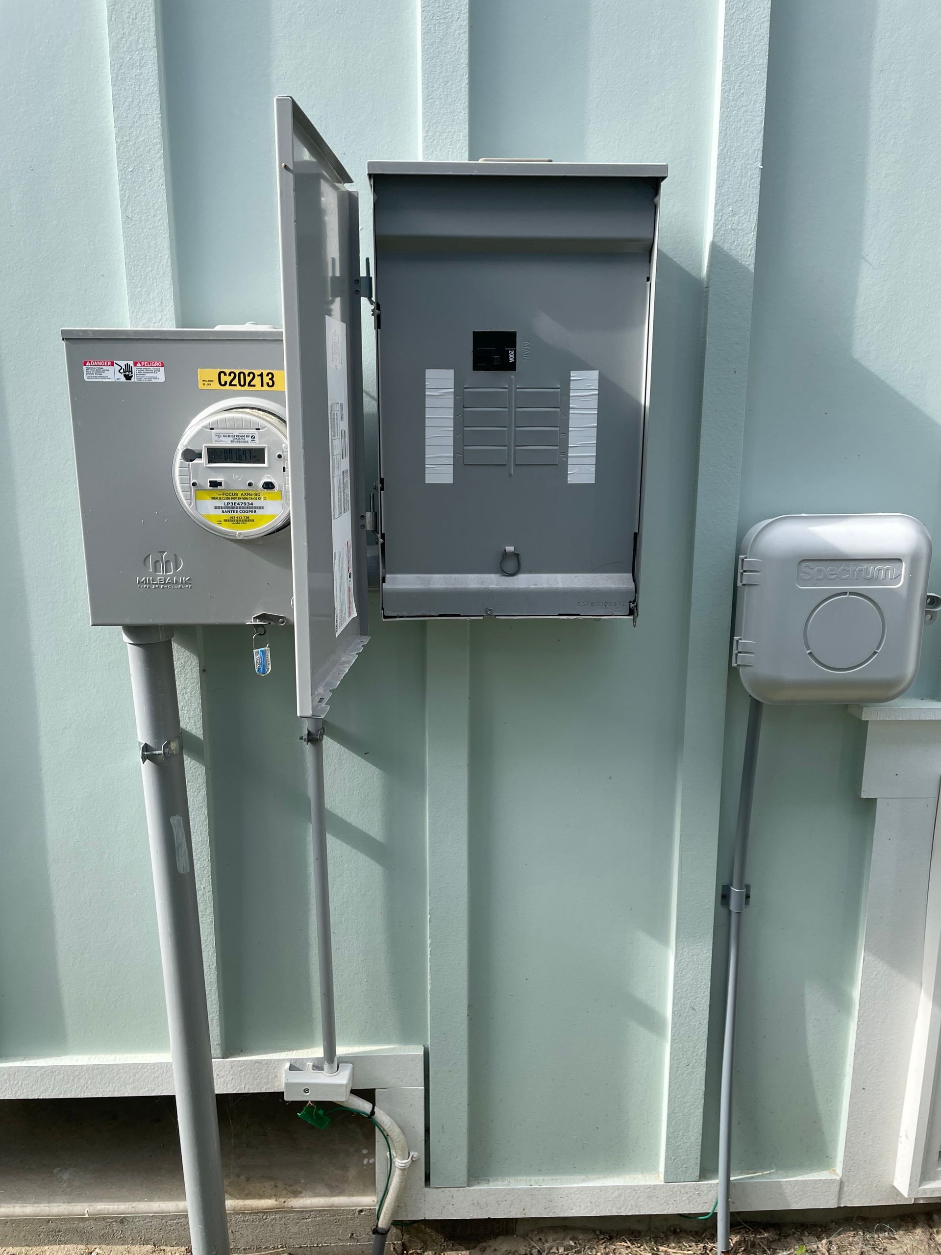 Electrician installing outlet. Blue-gloved hands, tools, yellow hardhat, and electrical wires.
