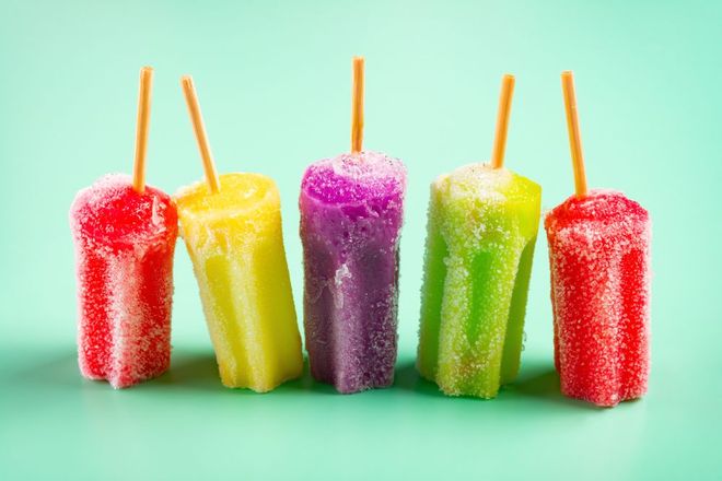 Five colorful popsicles—red, yellow, purple, green, red—standing on sticks against a mint background.