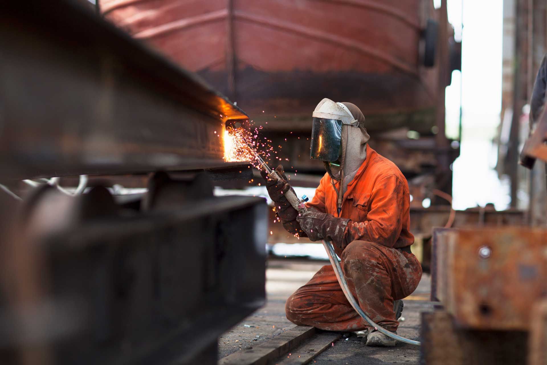 A man is welding a piece of metal in a factory.