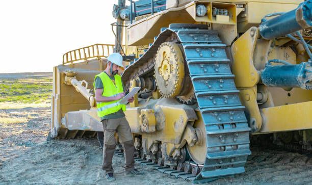 A man is standing next to a bulldozer on a construction site.