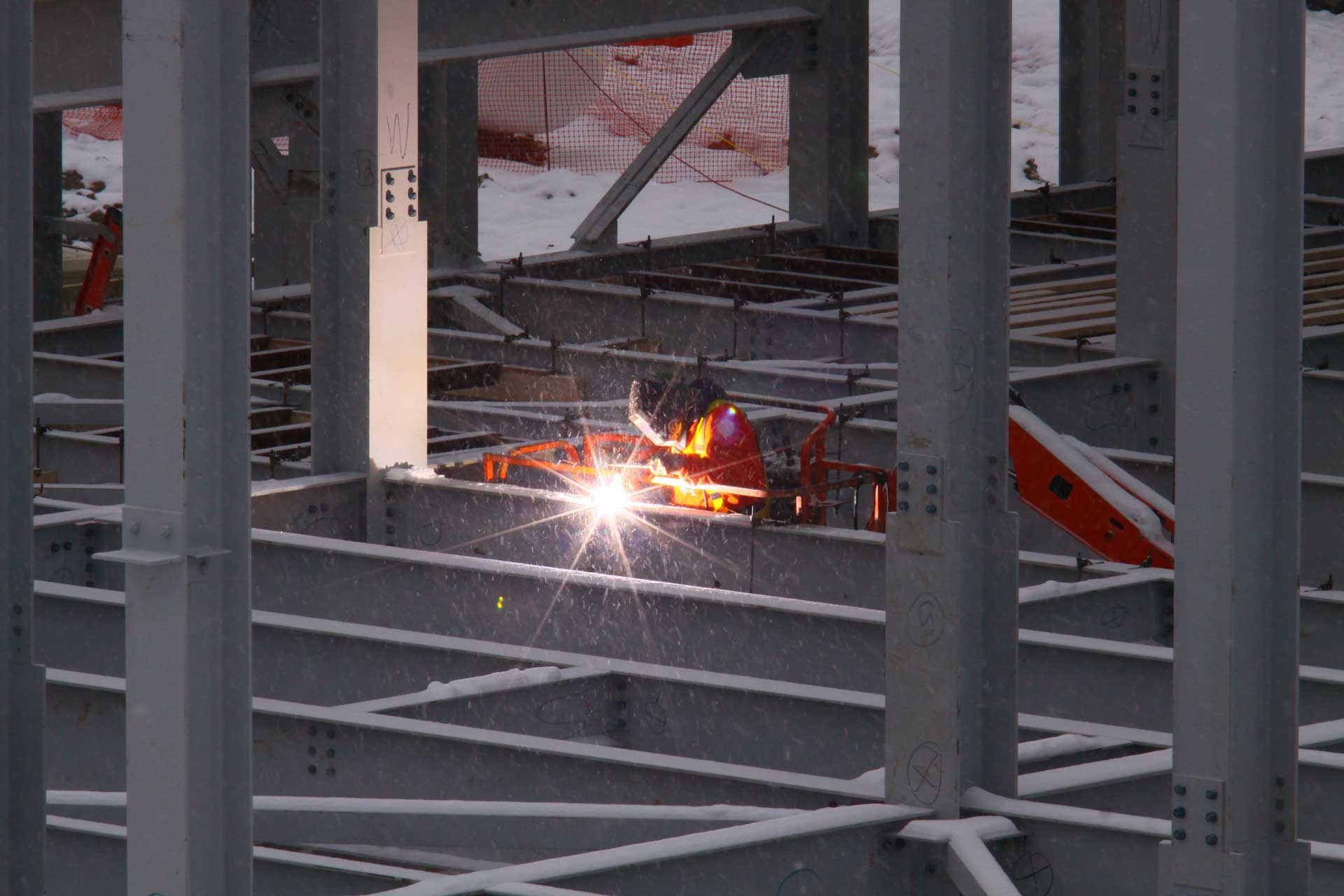 A man is welding a metal structure on a construction site.