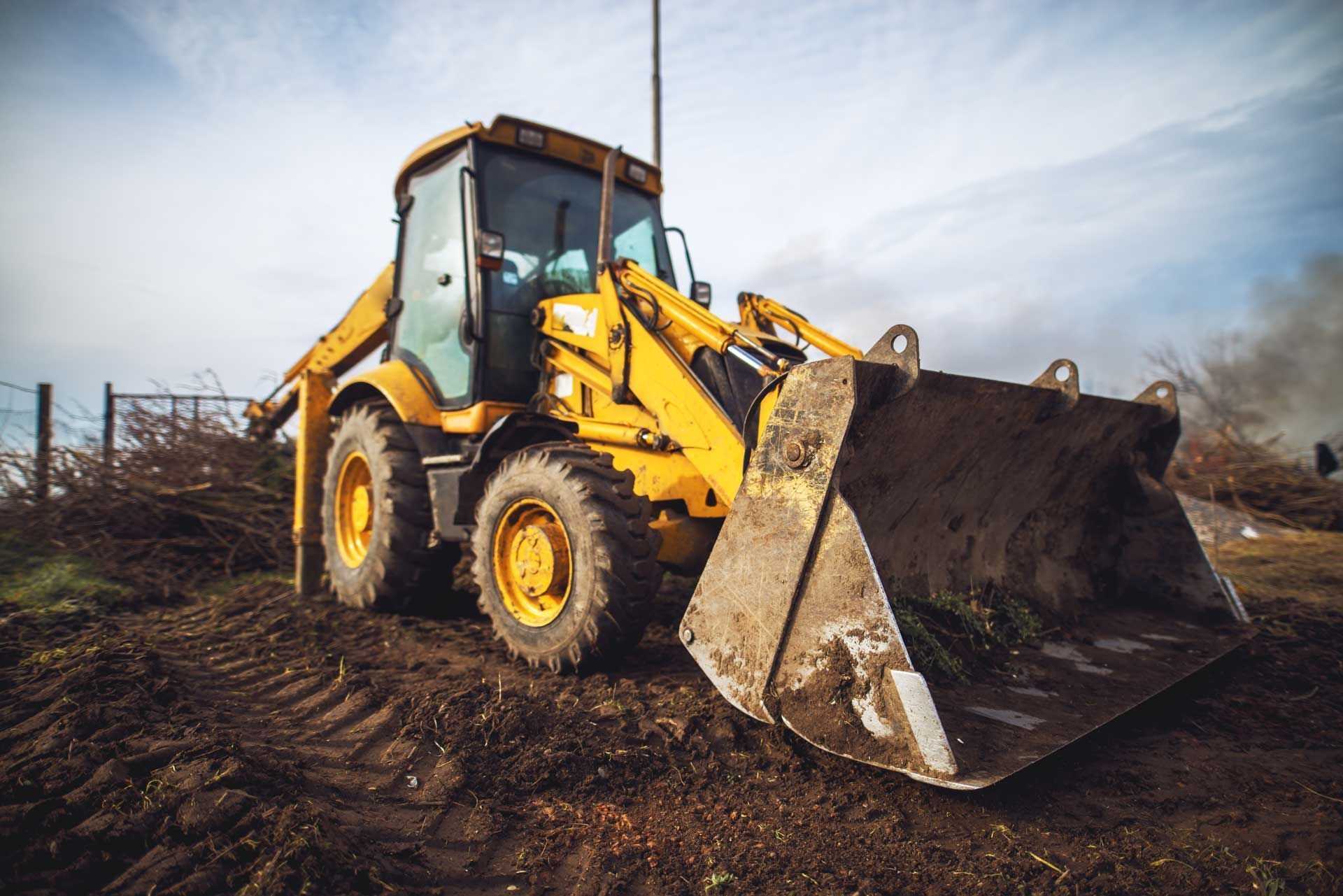 A yellow bulldozer is sitting on top of a dirt field.